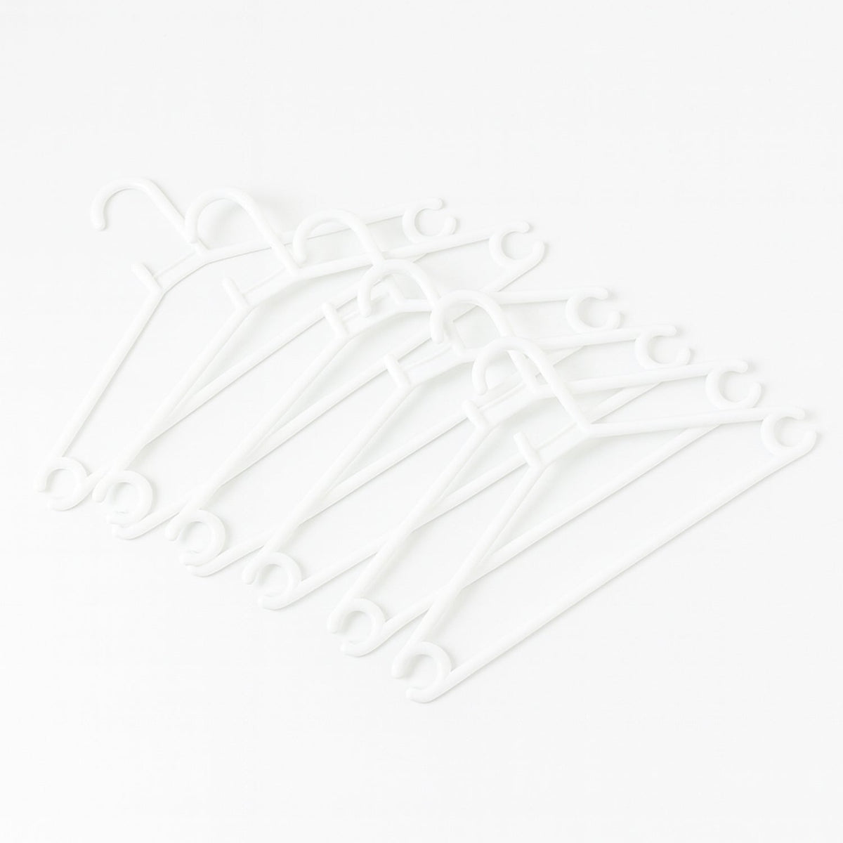 Stack of 6 white plastic clothes hangers ready for use
