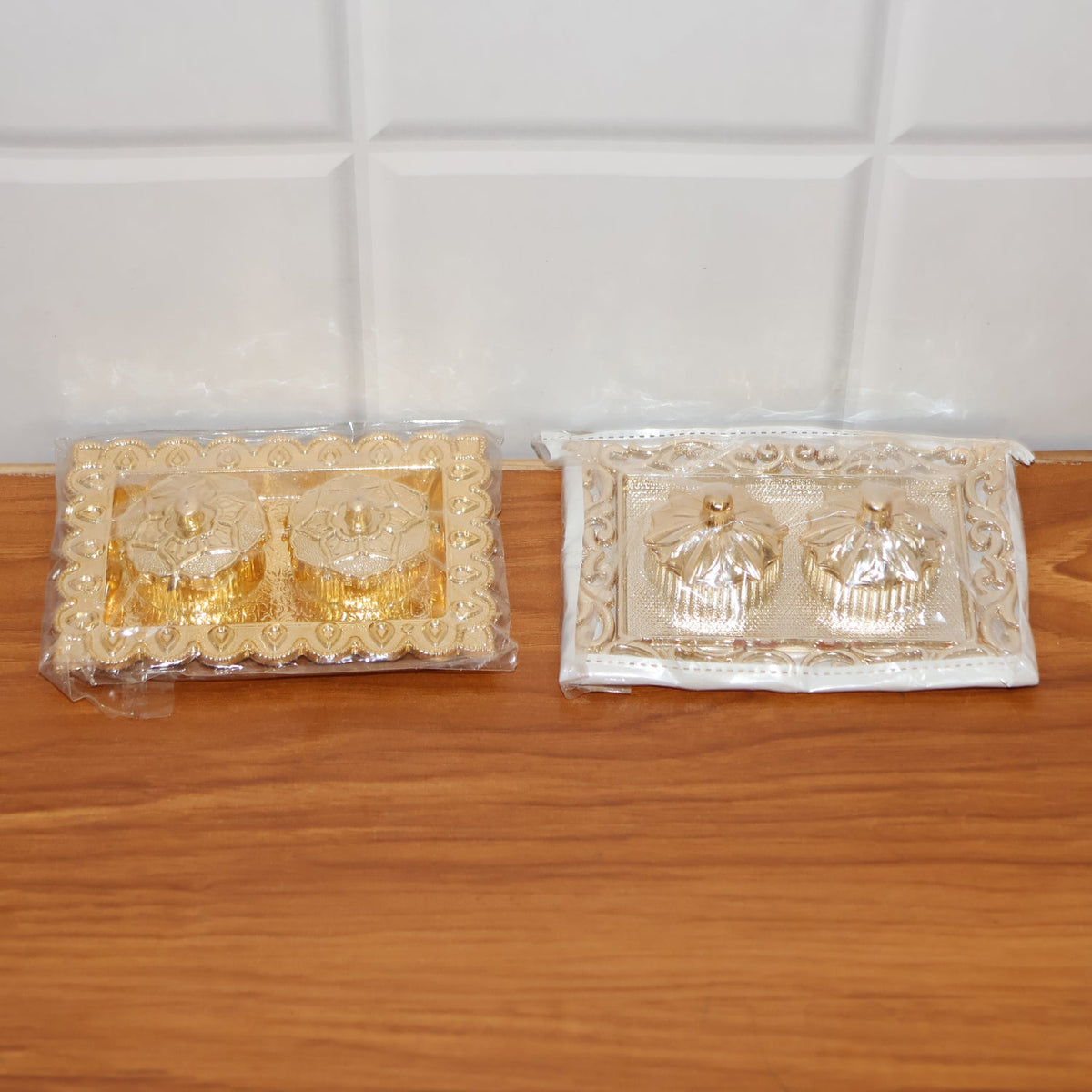 Hands holding the ornate rectangular pooja thali with flower-lid kumkum box