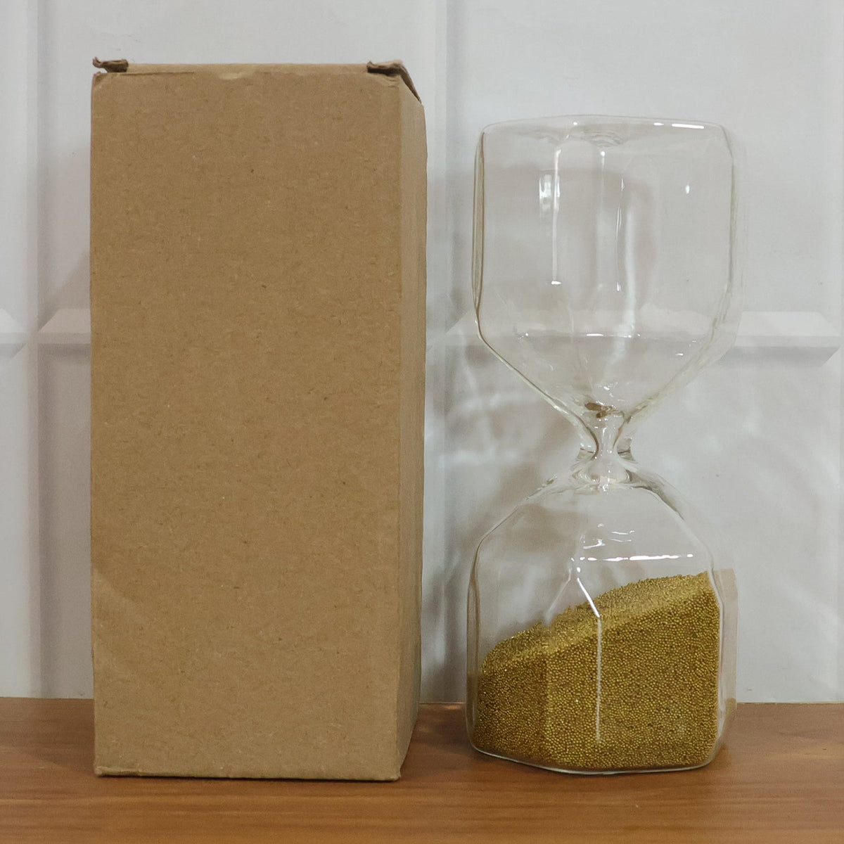 Clear glass 4-minute sand timer hourglass on a clean white background.